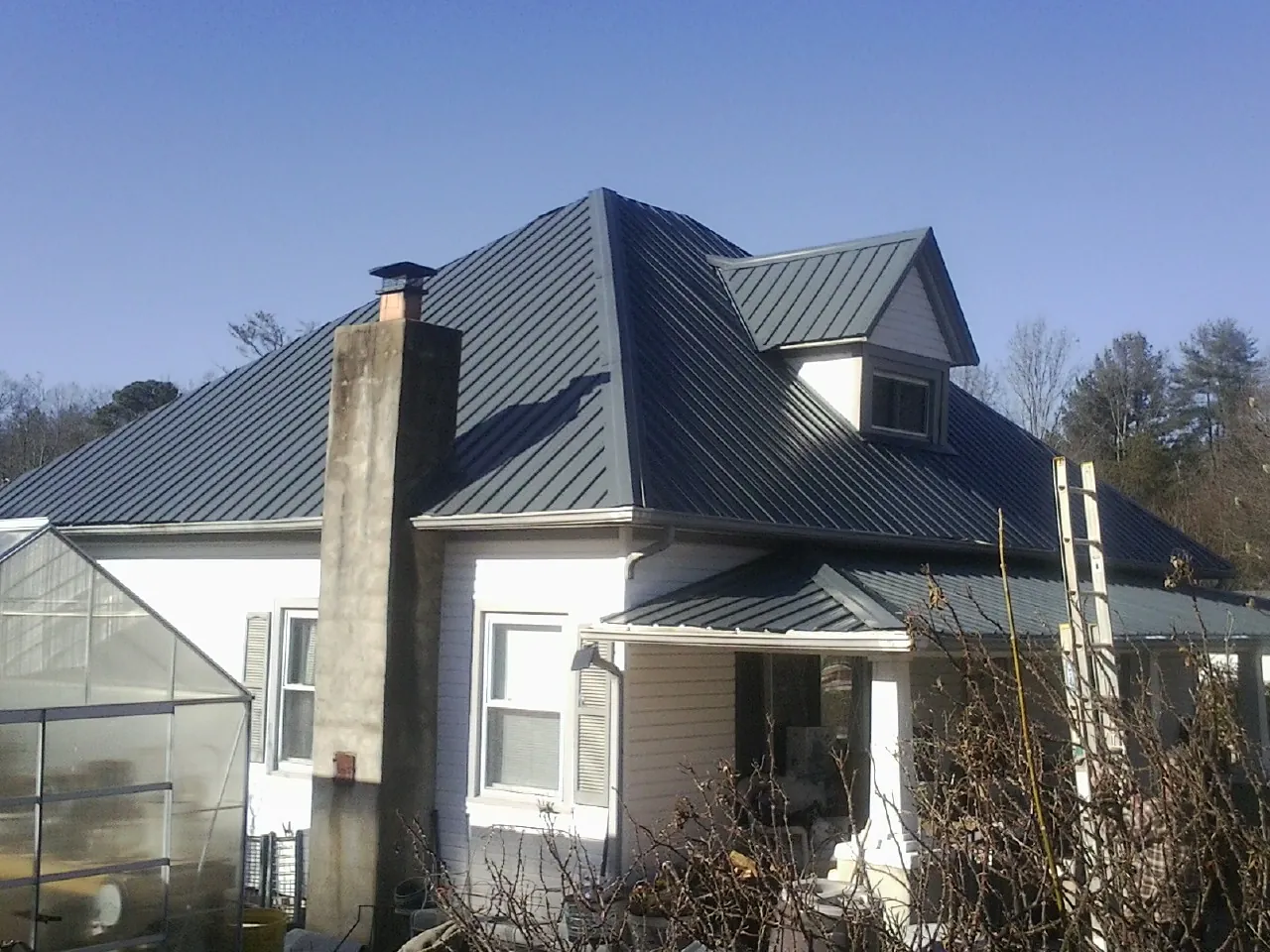 Dark blue standing seam metal roof on a white farmhouse with dormer — Slate & Tile Roof Repair by Roofing Brothers in Smock