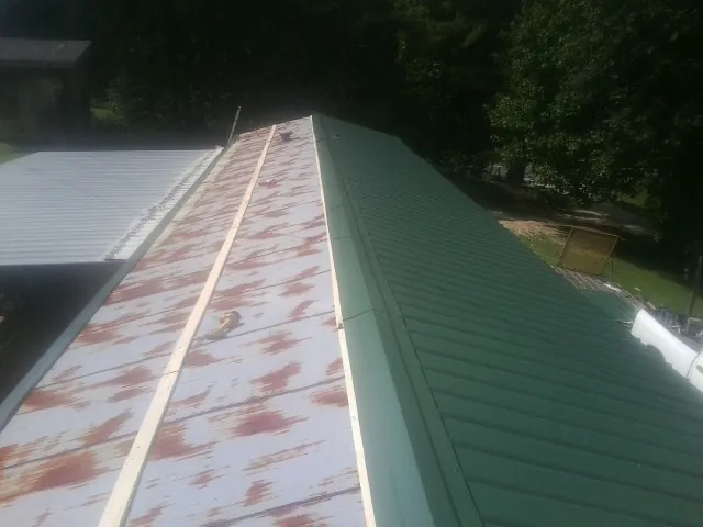 Old rusted panels beside newly installed green metal roofing — Wind Damage Roof Repair by Roofing Brothers in Smock