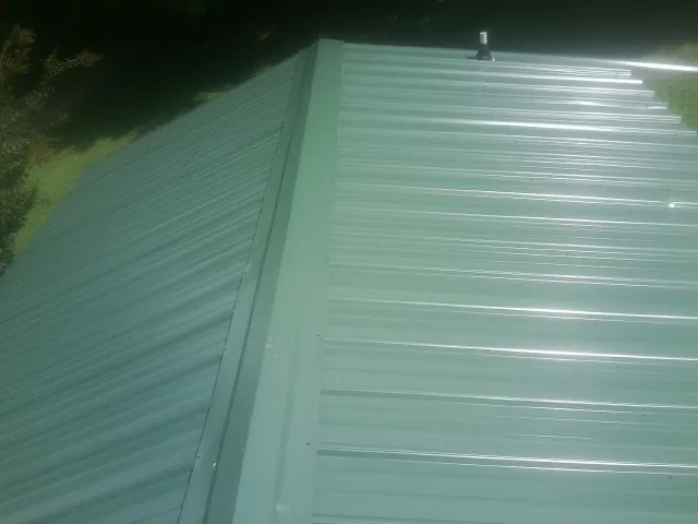 New green metal panels meeting at the ridge of a roof — Flat Roof Repair work by our crew in Smock