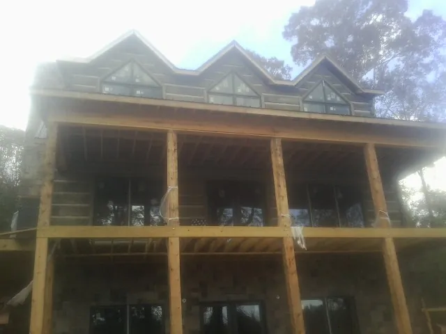 Dormers and porch framing on a large log home under construction — Roof Coating work by our crew in Smock