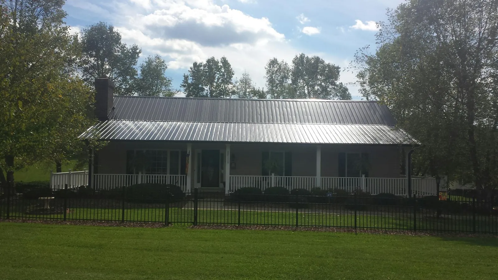 Gray metal roof on a brick ranch with a full width front porch — Gutter Guard Installation work by our crew in Smock