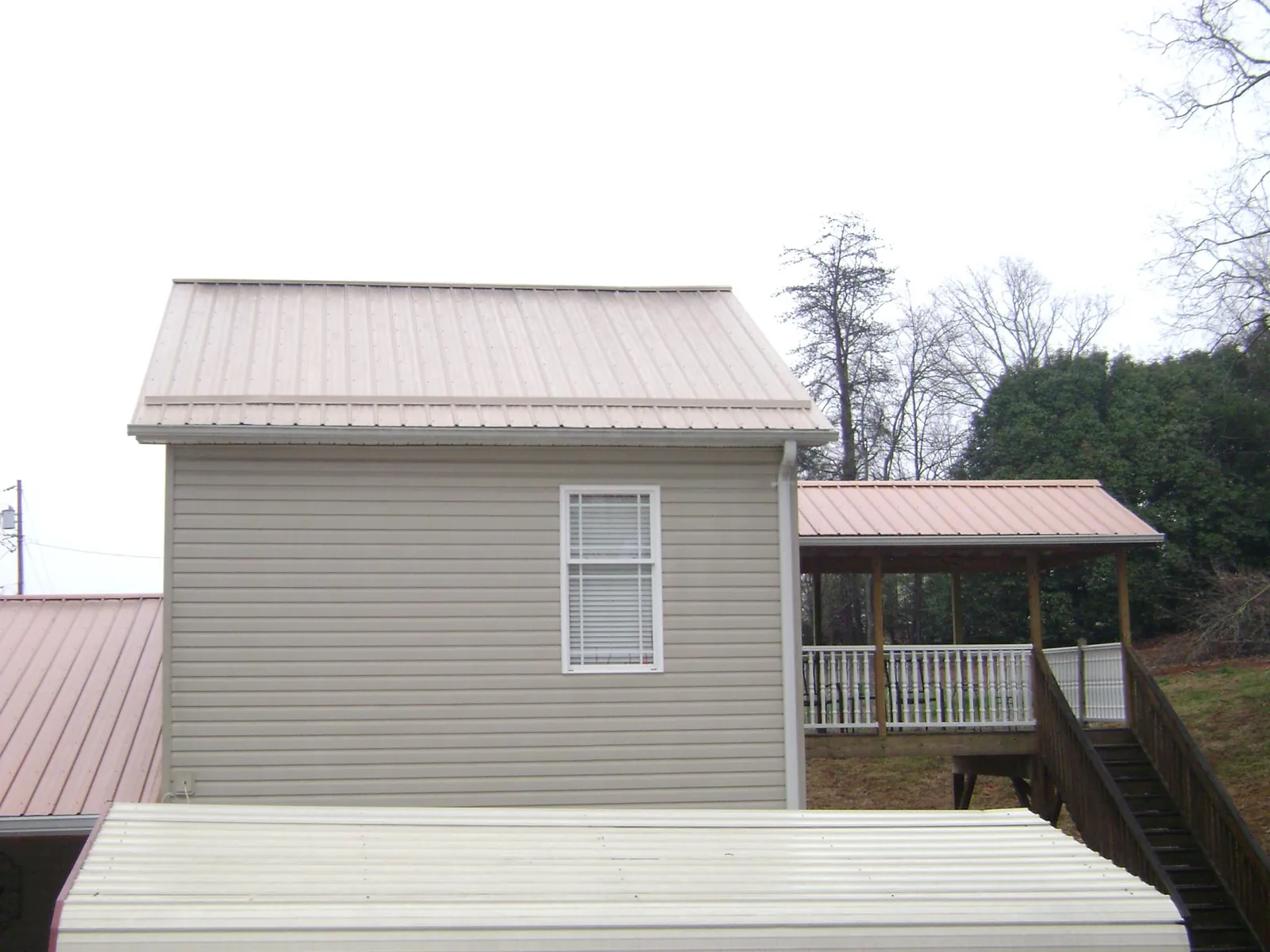 Tan metal roofs on a two story addition and attached porch, from a Roof Replacement job in Smock
