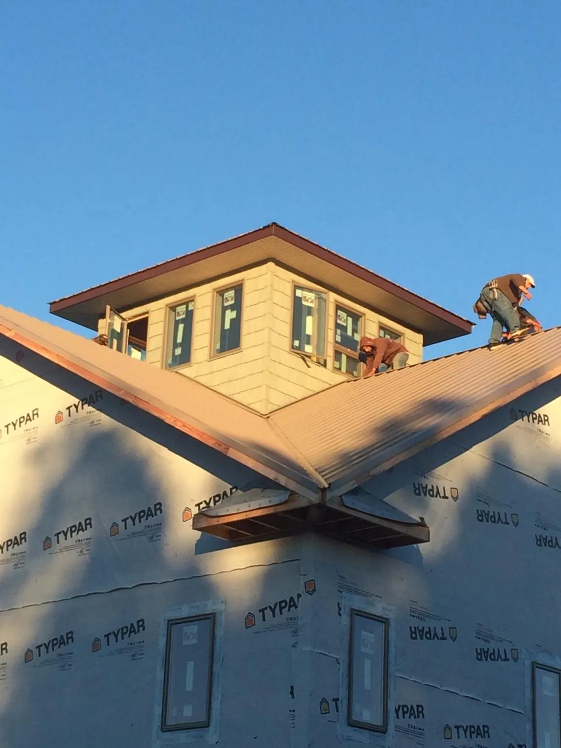 Roofers working around a rooftop cupola on a new metal roof at sunset — Roof Waterproofing in Smock by Roofing Brothers